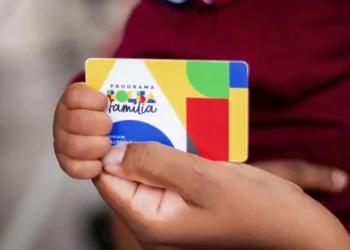 Cartão do Programa Bolsa Família sendo segurado por uma criança.