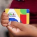 Cartão do Programa Bolsa Família sendo segurado por uma criança.