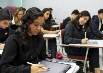 Estudantes concentrados escrevendo em tablets durante aula em sala de aula.