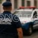 Guarda Municipal de costas ao lado de viatura durante concurso público.