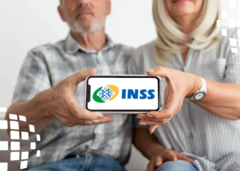 Casal segurando celular com logo do INSS na tela.