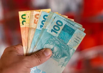 Pessoa segurando notas de reais de diferentes valores.