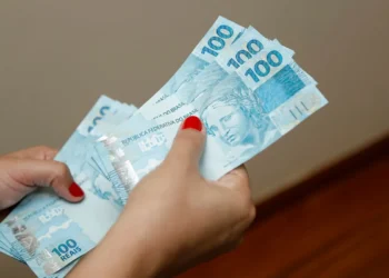 Pessoa segurando várias notas de 100 reais
