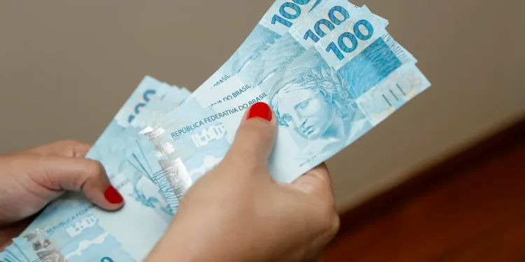 Pessoa segurando várias notas de 100 reais