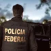 Agente da Polícia Federal de costas durante operação ao anoitecer.