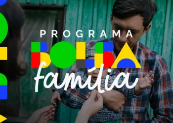 Pai segurando criança em frente a casa simples, representando o impacto social do Bolsa Família.