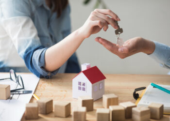 Pessoa entregando chaves de uma casa para outra, simbolizando a compra de imóveis e as oportunidades disponíveis a partir de R$ 33 mil.