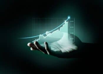 Mão segurando gráfico holográfico ascendente com valores financeiros simbolizando crescimento de investimentos