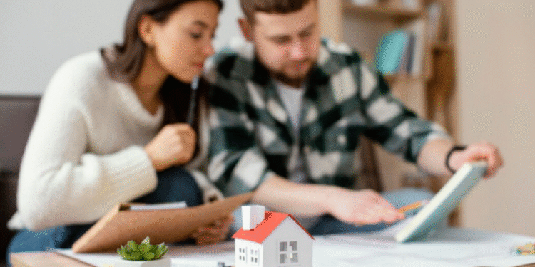 A imagem de um casal analisando plantas de uma casa, com um modelo de miniatura de uma casa na mesa, simbolizando o planejamento da compra de um imóvel.