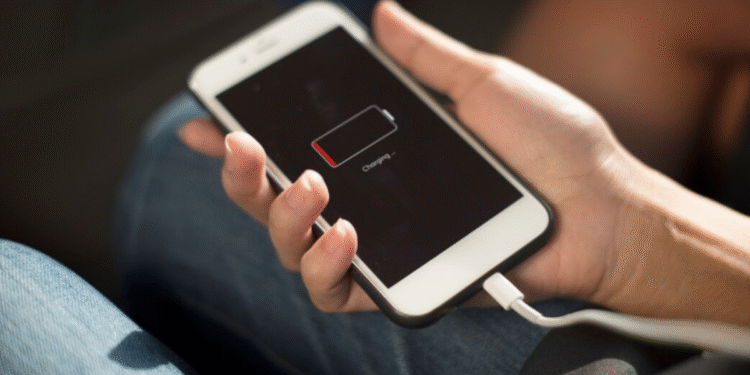 A imagem de um celular com a bateria fraca carregado por um cabo.