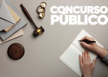 Mesa com martelo judicial, livros e mão escrevendo em caderno, com texto "Concurso Público".