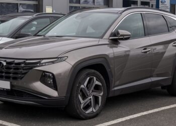 A imagem de um Hyundai Tucson 2024 estacionado em uma rua, visto de frente e de lado.