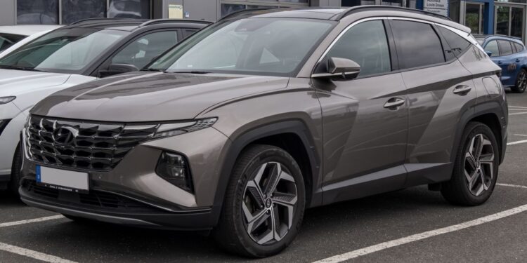 A imagem de um Hyundai Tucson 2024 estacionado em uma rua, visto de frente e de lado.