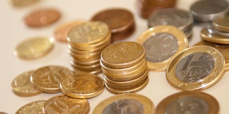 Pilha de moedas brasileiras mostrando o potencial de economia diária que se transforma em uma boa quantia no final do ano.