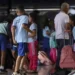 Alunos chegam à escola com mochilas e materiais escolares.