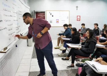 Professor escrevendo no quadro durante aula com alunos atentos