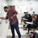 Professor escrevendo no quadro durante aula com alunos atentos