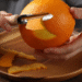 Descascando uma laranja com um utensílio de cozinha, representando o uso de cascas de laranja para aromatizar armários.
