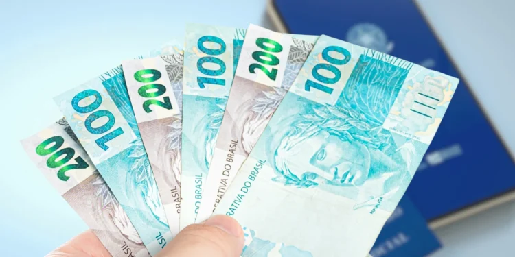 Cédulas de R$ 100 e R$ 200 ao lado da Carteira de Trabalho Digital.