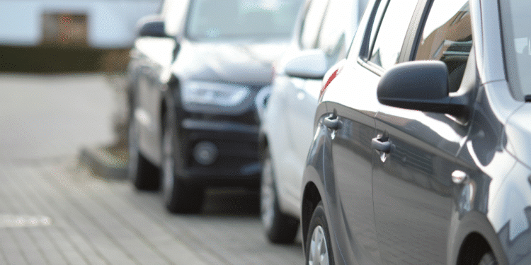 Automóveis estacionados lado a lado em uma calçada urbana pavimentada