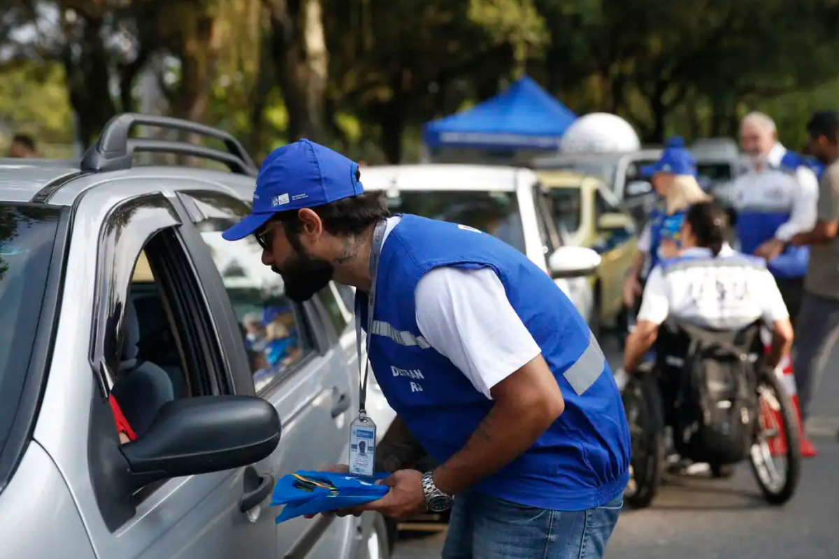 Concurso Detran Agente de trânsito aborda motorista em ação de fiscalização educativa nas ruas.