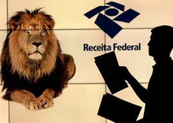 Pessoa segurando papéis com a imagem de um leão e o logo da Receita Federal ao fundo. Imagem ilustrativa sobre a devolução de dinheiro do Imposto de Renda.