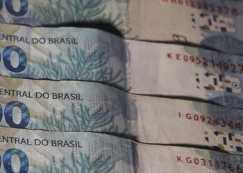 Cédulas de 100 reais dispostas de forma ordenada.