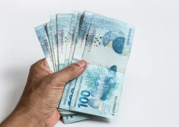 Mão segurando cédulas de 100 reais em leque