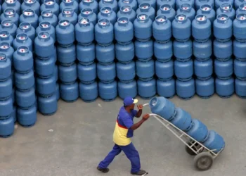 Homem trabalhando com botijões de gás em um armazém, relacionado à oferta de gás de cozinha gratuito pelo governo.