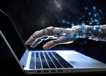 Mão robótica interagindo com teclado de notebook iluminado, tecnologia avançada