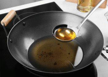 Concha com óleo de cozinha sobre frigideira em fogão elétrico moderno.