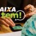 Aplicativo Caixa Tem exibido em smartphone ao lado de cédulas de 100 reais