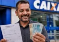 Homem segura cédulas e documento do Imposto de Renda, representando o pagamento do 4º lote da restituição do Imposto de Renda 2026.