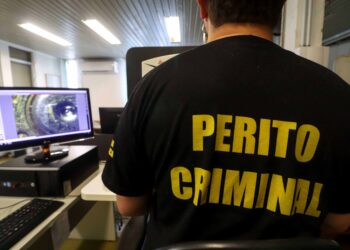 Perito criminal trabalha em computador analisando provas digitais em laboratório forense.