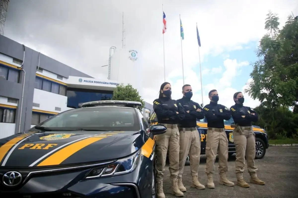 Policiais Rodoviários Federais: Remuneração de 2025 Policiais da PRF em frente à base, mostrando o comprometimento e a segurança nas rodovias brasileiras. O salário inicial de 2025 é de R$ 11.670,33.