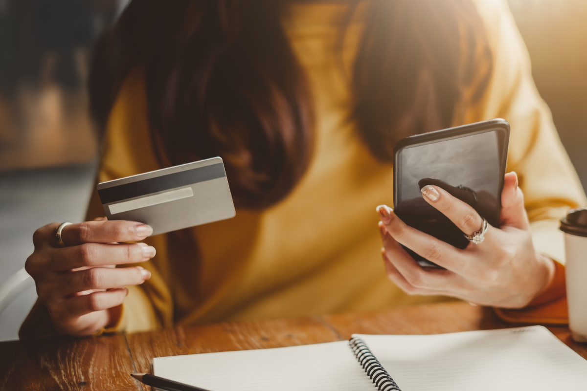 Cartão de crédito Mulher segurando cartão de crédito e smartphone, realizando compra online
