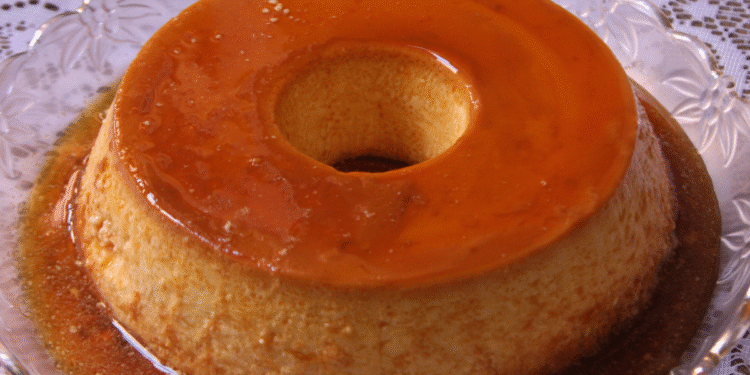 Pudim de leite condensado com calda de caramelo sobre prato de vidro.