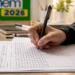 Estudante treinando redação do Enem 2026 com folha de prova e caneta sobre a mesa de estudos.