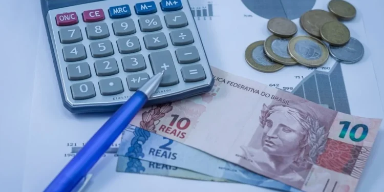 Calculadora, moedas, cédulas de reais e gráficos de reembolso de conta de luz.