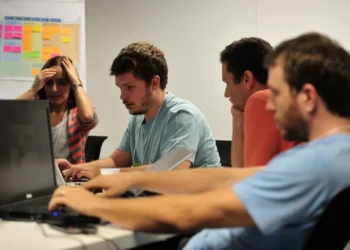 Equipe reunida em frente a computadores durante projeto colaborativo.