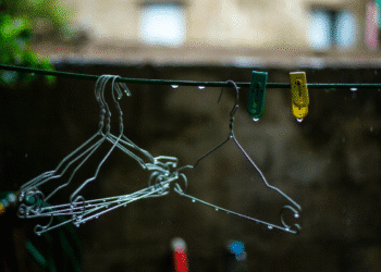 Cabides de arame e pregadores coloridos em um varal com gotas de chuva.