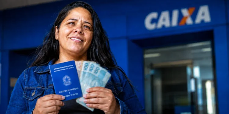 Trabalhadora segura documentos e dinheiro em frente a uma agência da Caixa representando o Saque Calamidade do FGTS