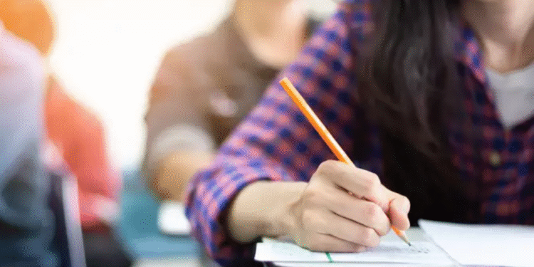 Pessoa escrevendo em uma folha durante o vestibular, representando os preparativos para os exames de 2026.