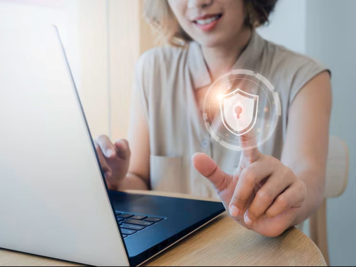 Segurança de Wi-Fi em 2025 Mulher interagindo com ícone de segurança digital em laptop, representando proteção de Wi-Fi