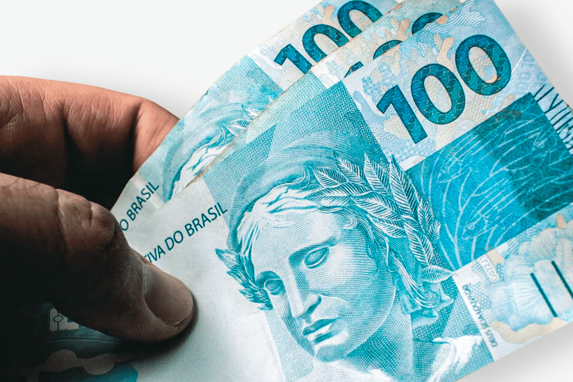 Mão segurando cédulas de 100 reais.
