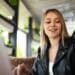 Jovem sorridente com cartão preto premium usando laptop em ambiente moderno