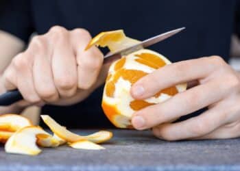 Pessoa descascando laranja com faca