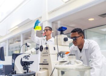 Dois jovens em laboratório realizando experimentos, representando as oportunidades de aprendizado técnico.