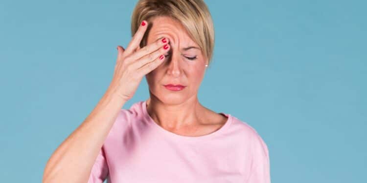 Mulher pressionando região temporal evidenciando incômodo causado por tremor involuntário na pálpebra