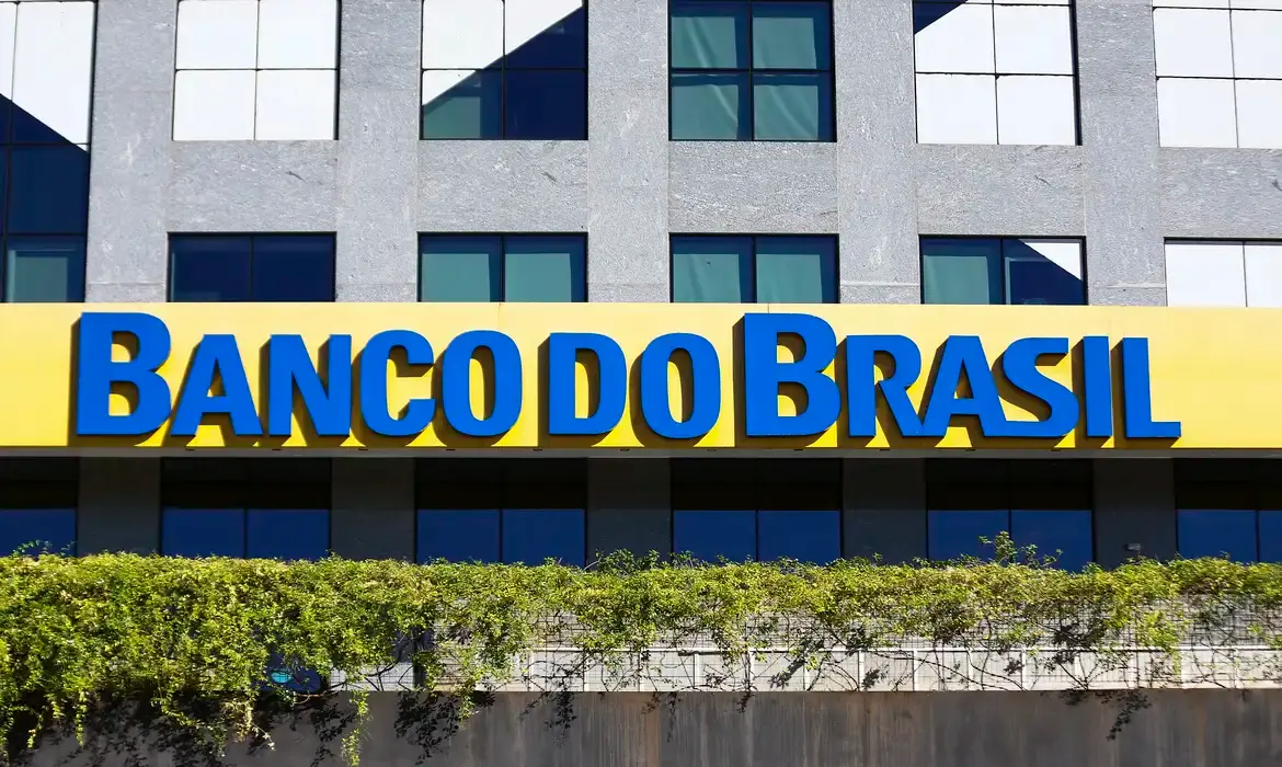 Banco do Brasil Logo do Banco do Brasil em fachada de agência, destacando a marca em azul sobre fundo amarelo.